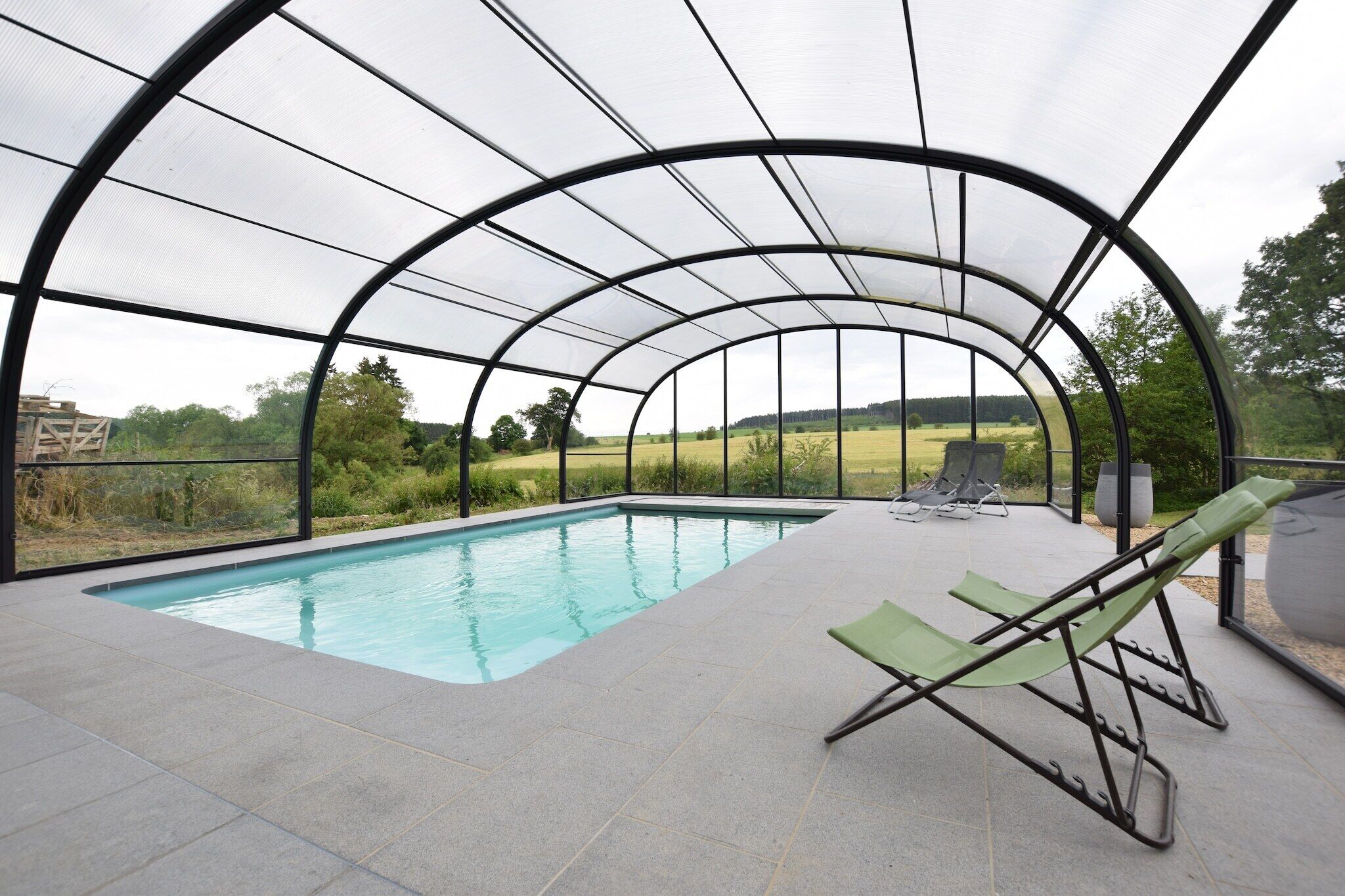 Una piscina coperta esterna con vista su un paesaggio verde.