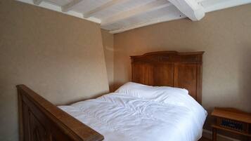 Een slaapkamer met een houten bed, een nachtkastje en een plafond met zichtbare balken.