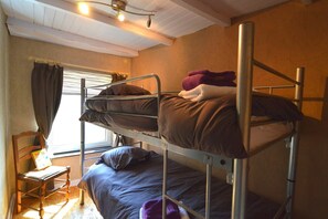 A bunk bed room with a window, a chair, and a book on the floor.