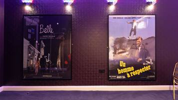 Two movie posters on a wall with patterned wallpaper and a carpeted floor.