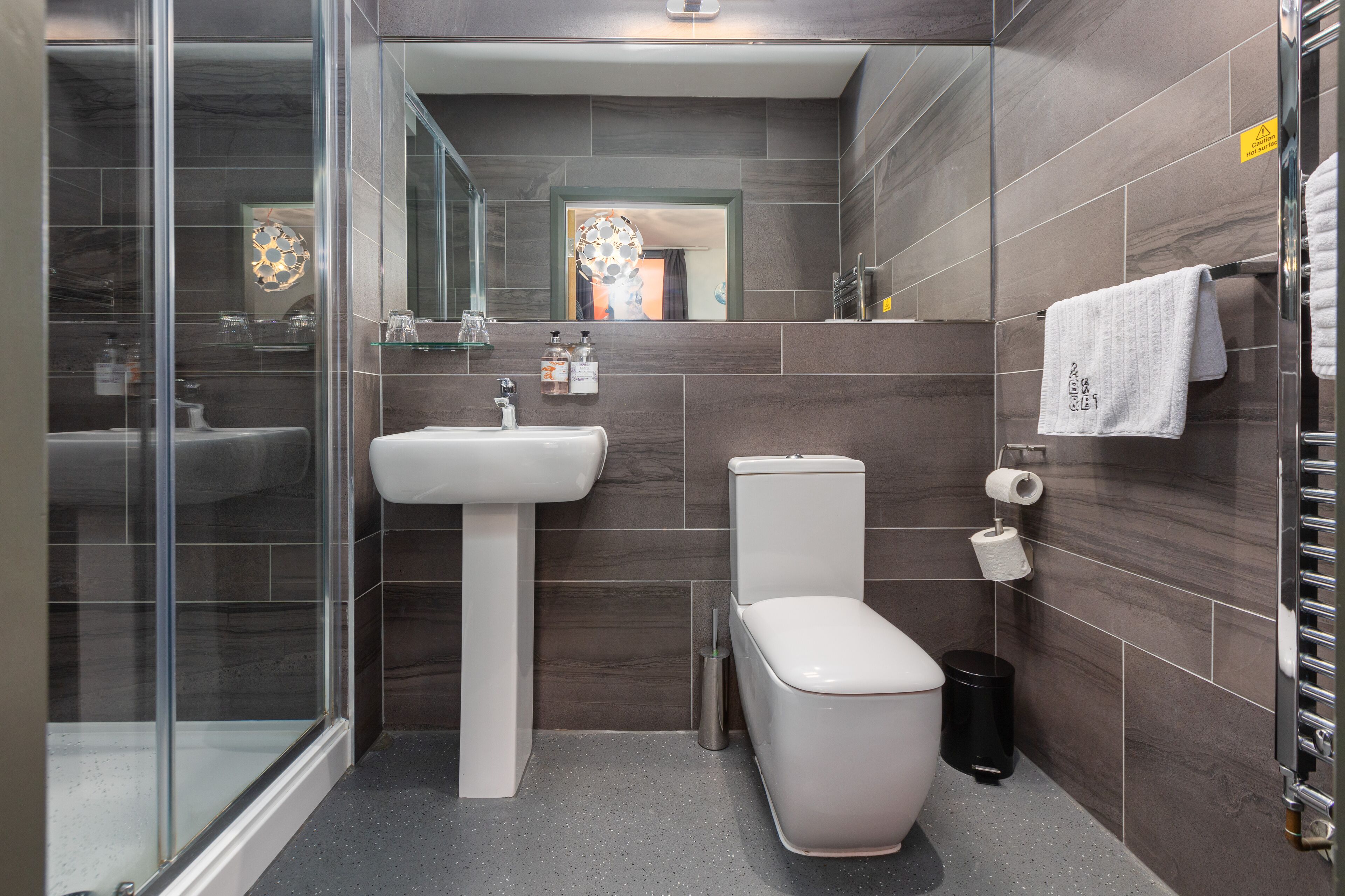 Un baño moderno con cabina de ducha de vidrio, un lavabo blanco y un inodoro.
