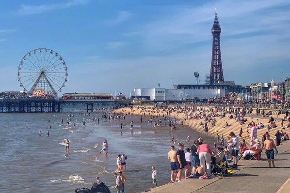 A crowded beach with a Ferris wheel and a tall tower in the background. - ART B&B (Blackpool)
