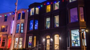 A multi-story building with illuminated windows and a visible storefront. - ART B&B (Blackpool)