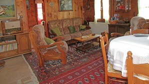 A cozy wooden cabin interior with a sofa, chairs, a table, and a bookshelf. - Boutique Apartment in Valais with Balcony (Guttet-Feschel)