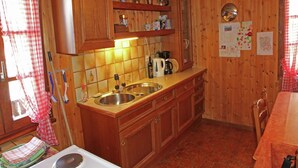 A wooden kitchen with two sinks, a stove, and a coffee maker. - Boutique Apartment in Valais with Balcony (Guttet-Feschel)