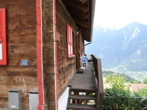 A wooden building with a balcony overlooking a mountainous landscape.