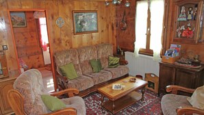 A traditional wooden interior with a sofa, chairs, a coffee table, and a patterned rug. - Boutique Apartment in Valais with Balcony (Guttet-Feschel)