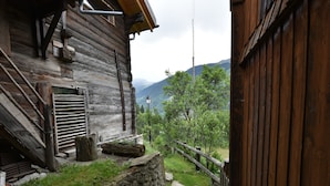 A rustic wooden building with a stone wall and a wooden staircase leading up to a door.