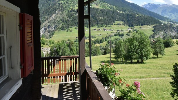 A wooden balcony with a view of a mountainous landscape.
