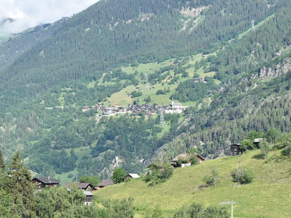 A mountain village with traditional wooden houses, a church, and a power line. - Cozy Stay near Aletsch (Grengiols)