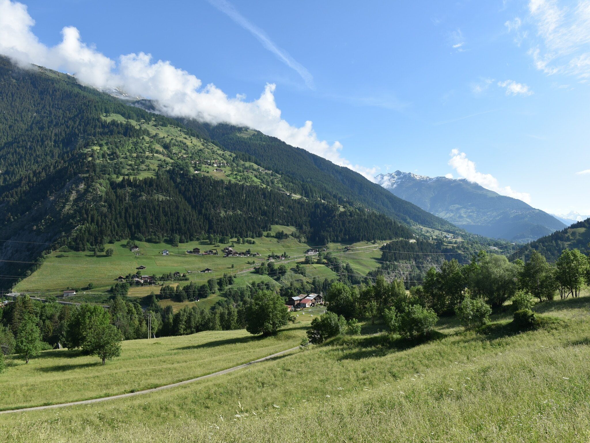 A mountainous landscape with a valley, scattered houses, and a clear sky.