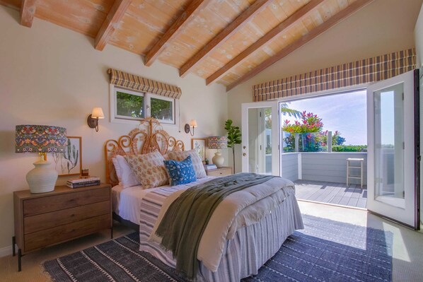 Un dormitorio con una cama grande, un aparador de madera, una mesita de noche y una ventana con vistas al exterior.