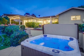 A hot tub in a backyard with a house in the background.