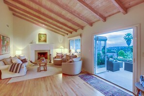 A spacious living room with a fireplace, comfortable seating, and a view of the outdoors. - Solana Beach House w/ Hot Tub & Ocean Views (Solana Beach)