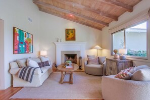 A cozy living room with a fireplace, two sofas, a coffee table, and a window with a view.