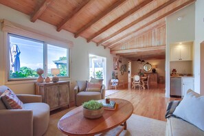 Un amplio salón comedor con techo alto, vigas de madera y cocina.