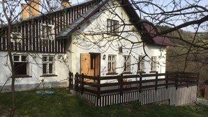 Ein weißes Haus mit einer Holzterrasse und einem roten Dach.