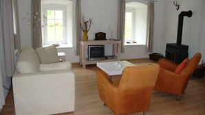 Un soggiorno con divano, due poltrone, tavolino, camino e televisione.
