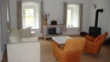 Un salon comprenant un canapé, deux fauteuils, une table basse, une cheminée et un téléviseur.
