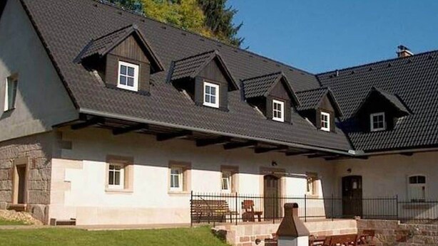 Un edificio con tetto spiovente, diverse finestre e facciata in pietra.