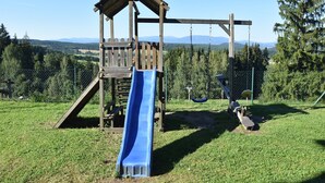 A playground with a slide, swings, and a wooden climbing structure.