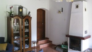 Un salon avec un meuble en bois, une horloge, une cheminée et un escalier.