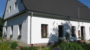 Un bâtiment blanc avec un toit foncé, de nombreuses fenêtres et une cheminée.