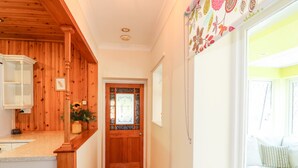 A wooden hallway with a door featuring decorative glass panels and a window with a view of a balcony.