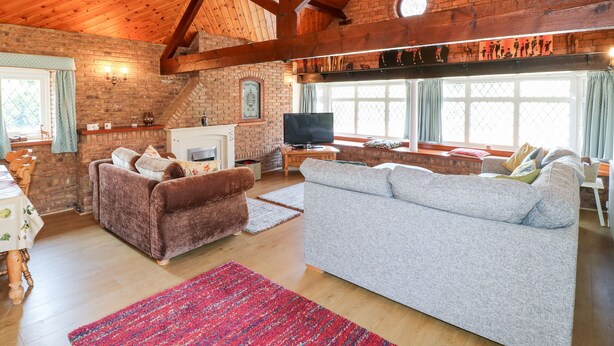 A cozy living room with a fireplace, wooden beams, a television, and comfortable seating.