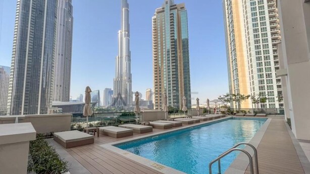 A rooftop pool with lounge seating and a view of tall buildings. - Maison Privee - Luxury 2Bedroom w/ Burj Khalifa & Fountain Views (Dubai)