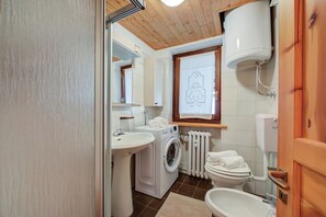 A bathroom with a washing machine, toilet, sink, and a radiator. - Appartamento Rochebrune 200m From Ski (Claviere)