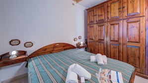 Un dormitorio con una cama de madera, un armario y una mesita de noche con una lámpara.