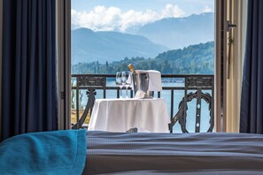 Un balcón con una mesa lista para dos, con vista a un lago y montañas.