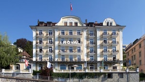 A multi-story hotel with balconies, a flag on top, and a stone facade.