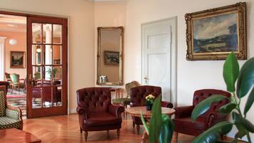 A room with a wooden floor, a round table with chairs, a mirror, and a door.