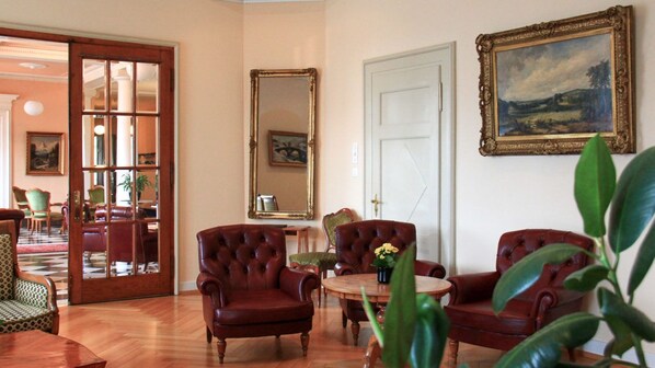 Una habitación con piso de madera, una mesa redonda con sillas, un espejo y una puerta.