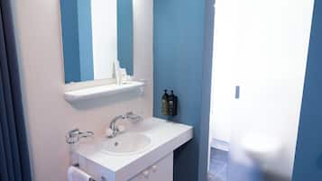 A bathroom with a white sink, a mirror, and a towel rack.