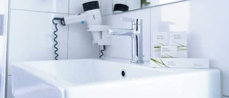 A modern bathroom with a white sink, chrome faucet, and a glass shower enclosure.