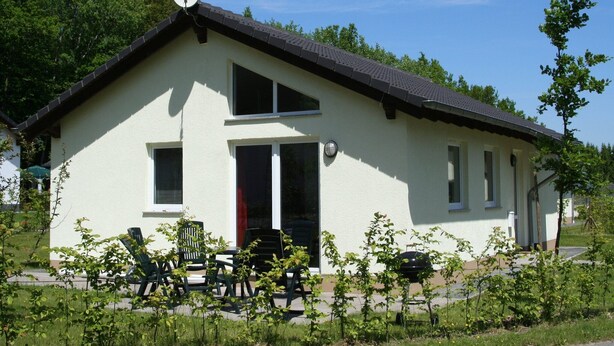 A single-story house with a sloped roof, a satellite dish, and a small porch with chairs. - Bungalow near Eifel Ski Lift (Hinterhausen - Gerolstein)