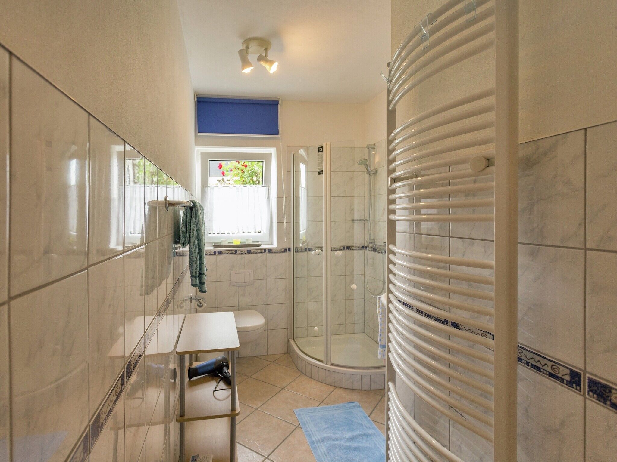 Un baño moderno con cabina de ducha de vidrio, un inodoro y un lavabo con toallero.