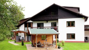A two-story chalet with a wooden deck and outdoor seating area.