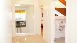 A hotel room with a balcony, a bathroom with a sink and mirror, and a wooden ceiling.