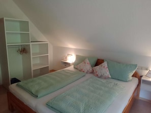 Une chambre à coucher comprenant un lit, une table de chevet, une armoire et une étagère fixée au mur.