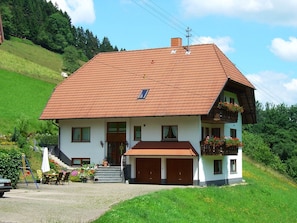 Une maison à deux étages, avec un toit en pente, un porche à l’avant et un garage.