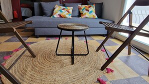 A living room with a grey sofa, colorful pillows, a woven rug, and two wooden chairs.
