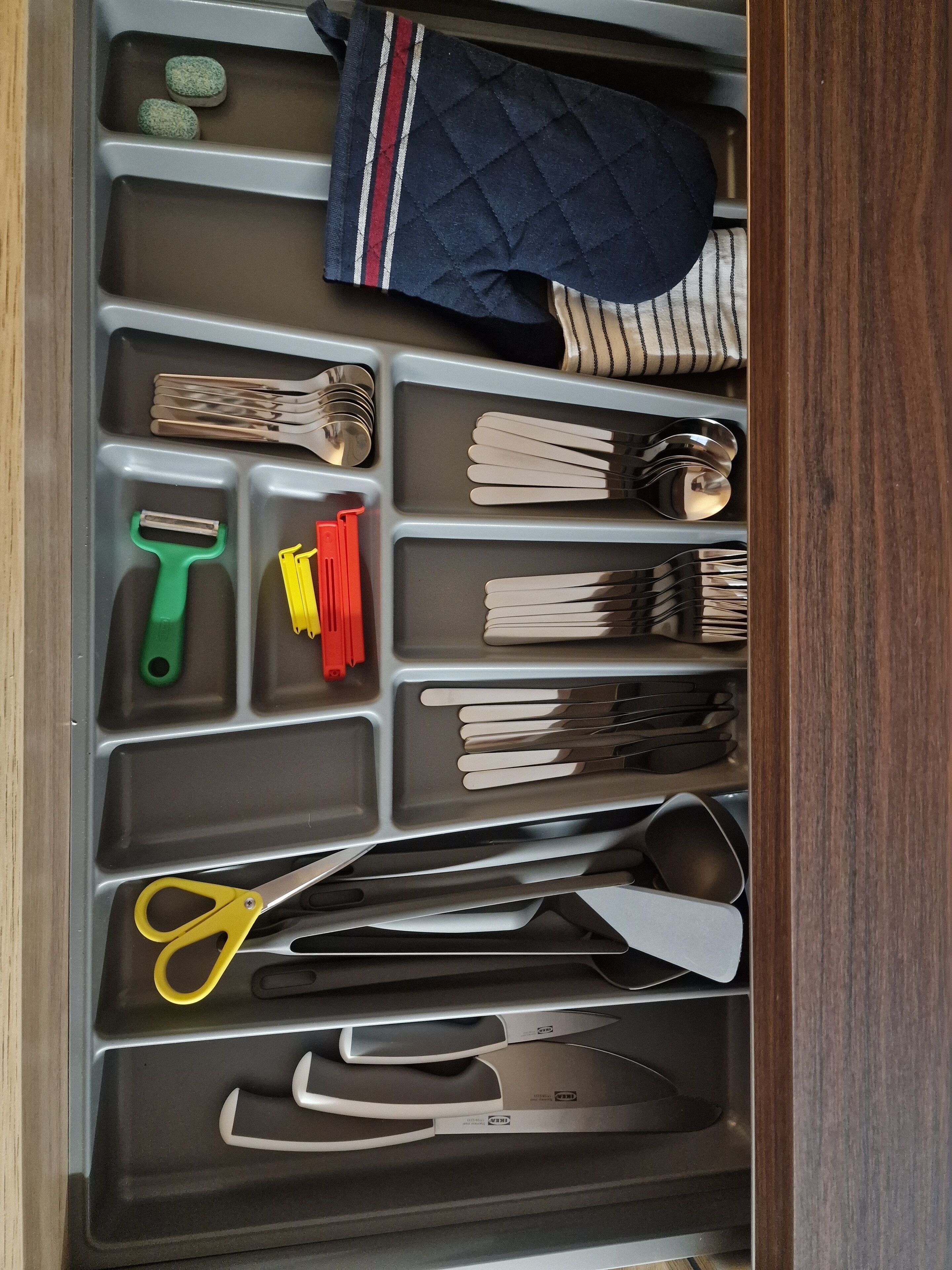 Een keukulaag met keukengerei en -gereedschap, netjes geordend in vakken.
