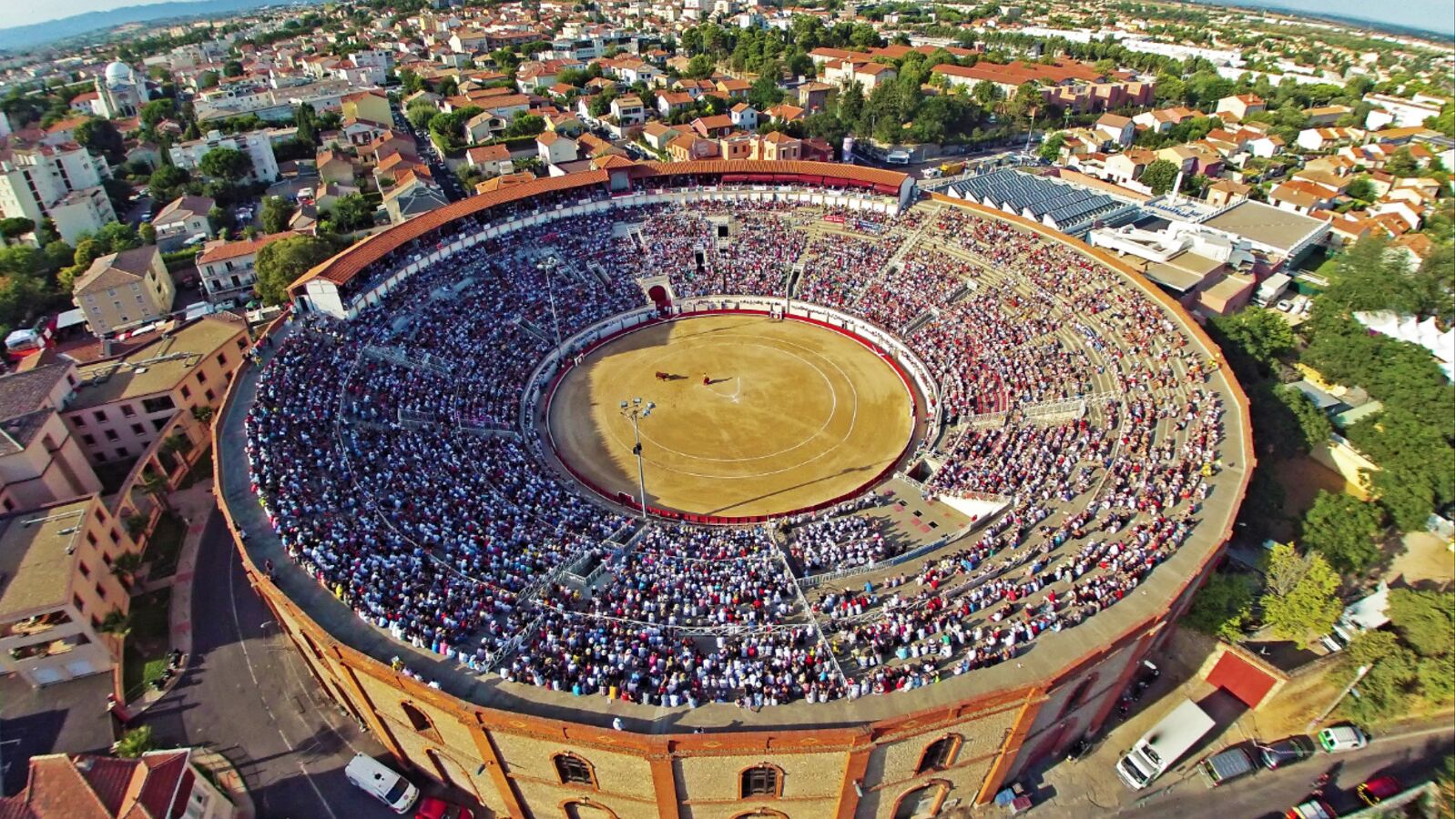 Un'ampia arena circolare per corrida, circondata da edifici urbani.