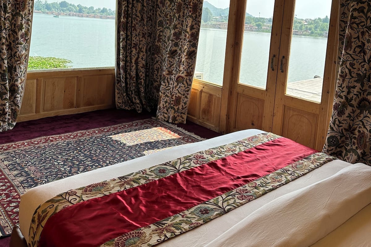 A room with a large bed, wooden ceiling, and a view of a lake.