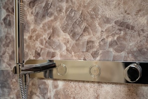 Shower features a sleek, adjustable head with a flexible hose and control panel.
