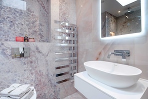 Features a large oval sink, sleek countertop, and shelf for toiletries.